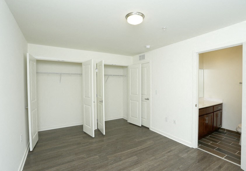 the living room of an empty apartment with white walls and wood flooring