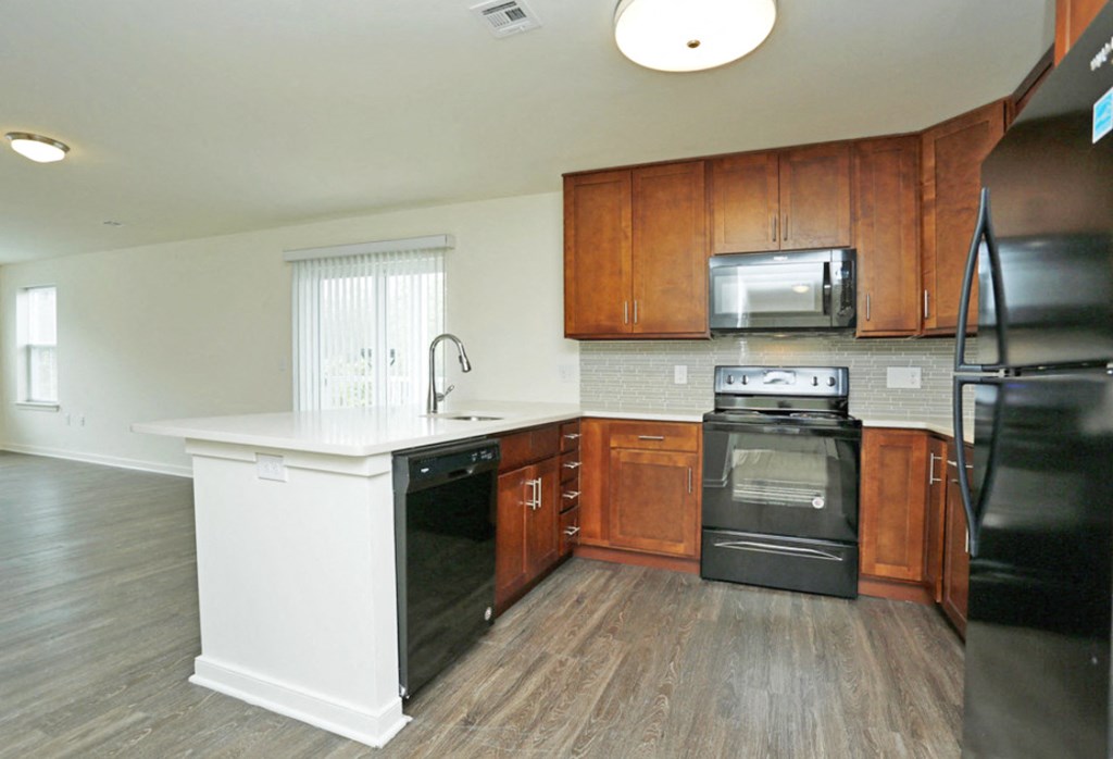 an empty kitchen with wooden cabinets and black appliances