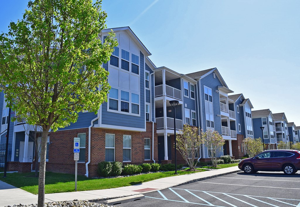 an apartment building with a red car parked in a parking lot