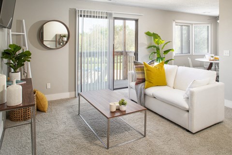 A living room with a white couch, a coffee table, and a mirror on the wall.