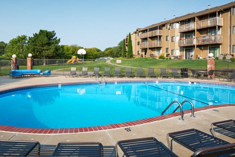 A large swimming pool with lounge chairs around it.