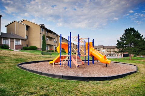 A playground with a yellow slide and a blue and orange climbing frame.