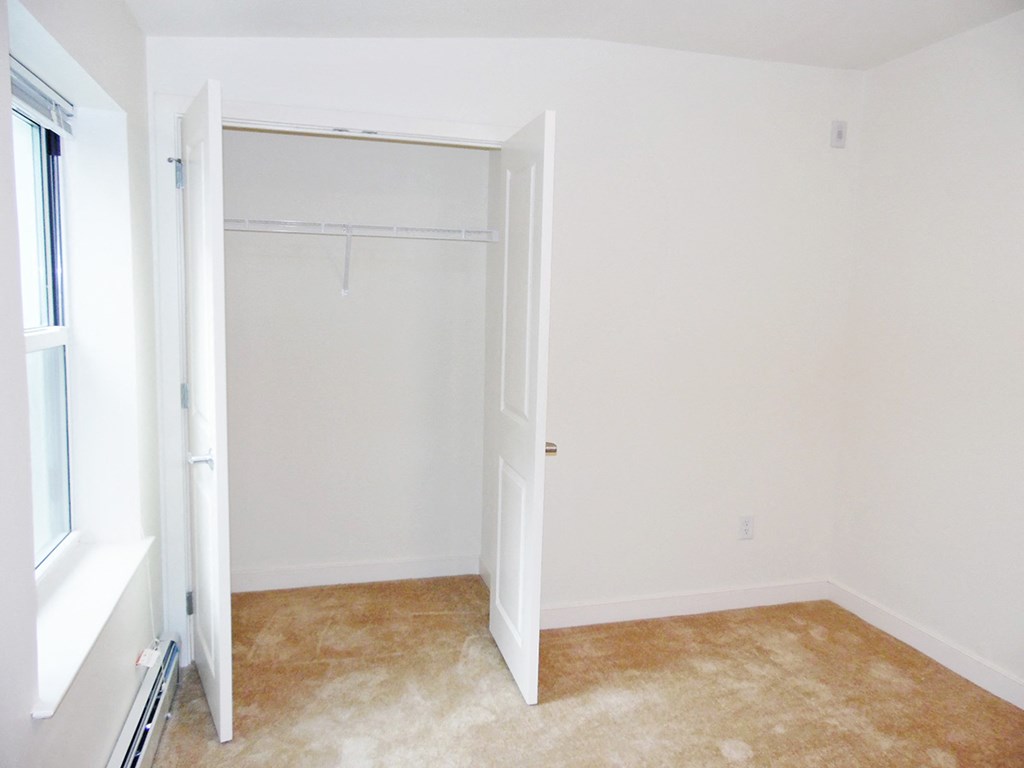 an empty room with a closet and a window