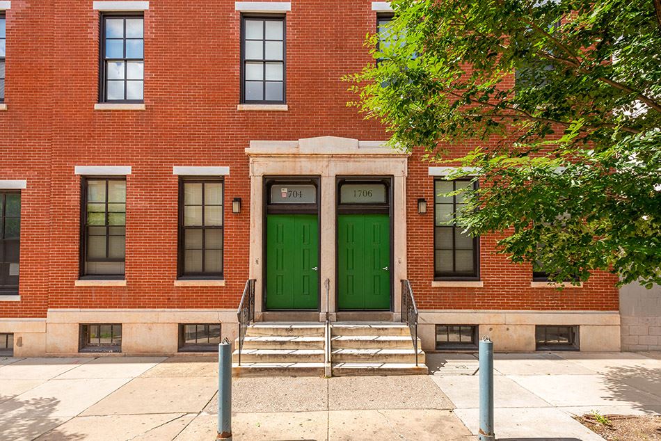 the front of a red brick building with green doors