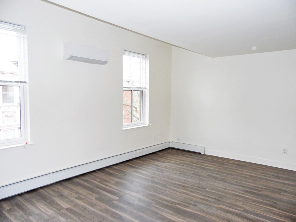 an empty room with white walls and wood floors and a window