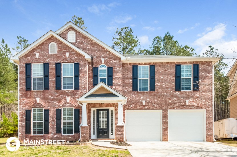 a brick house with black shutters and a white garage door