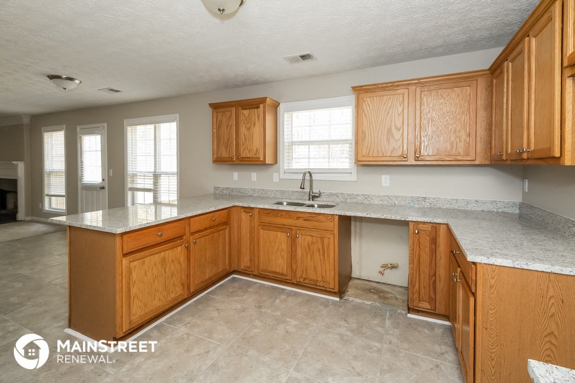 a kitchen with wooden cabinets and white counter tops and a sink