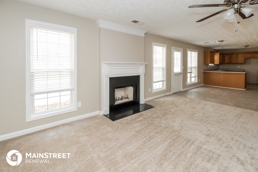 a living room with a fireplace and a kitchen