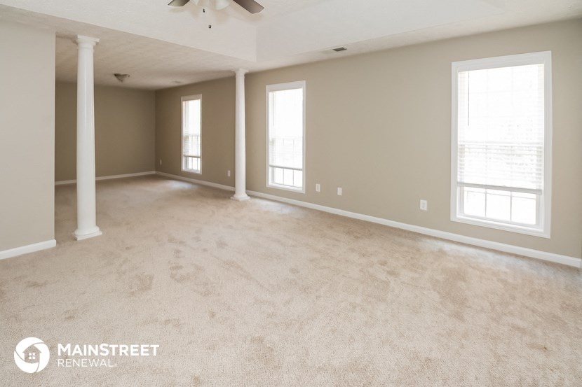 the living room of a new home with carpet and windows