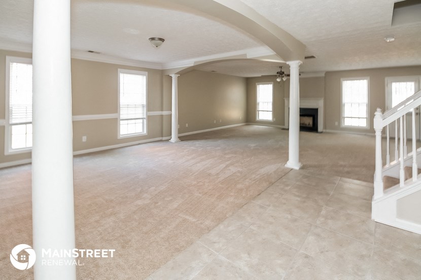 an empty living room with white pillars and a staircase