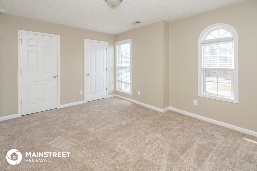 a living room with two doors and a carpeted floor