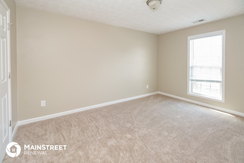 the upstairs bedroom with carpeted flooring and a large window