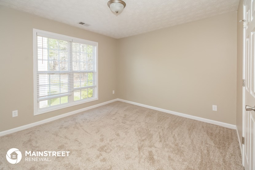 a bedroom with a carpeted floor and a large window