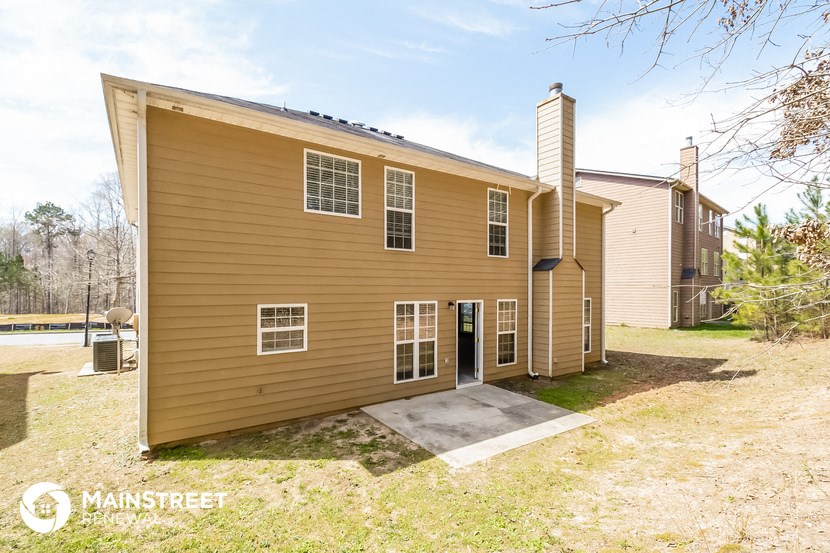 the back of a yellow house with a ramp to a driveway