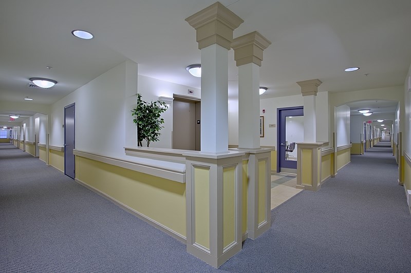 an empty hallway in a hospital with white columns and blue doors