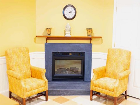 a living room with yellow chairs and a fireplace