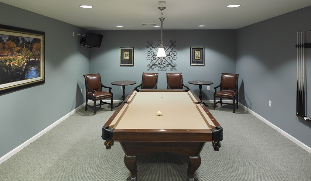 a game room with a pool table and chairs