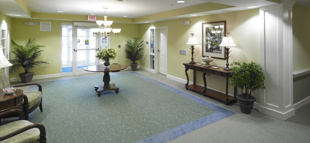 a lobby with a blue carpet and a table with plants