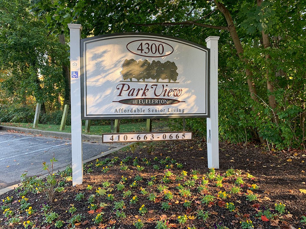a sign in front of a park with trees