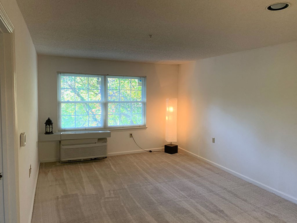 an empty living room with a large window and a radiator