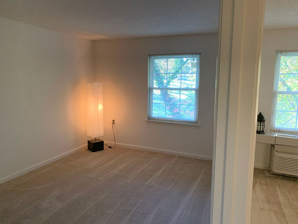 an empty living room with a lamp and a window