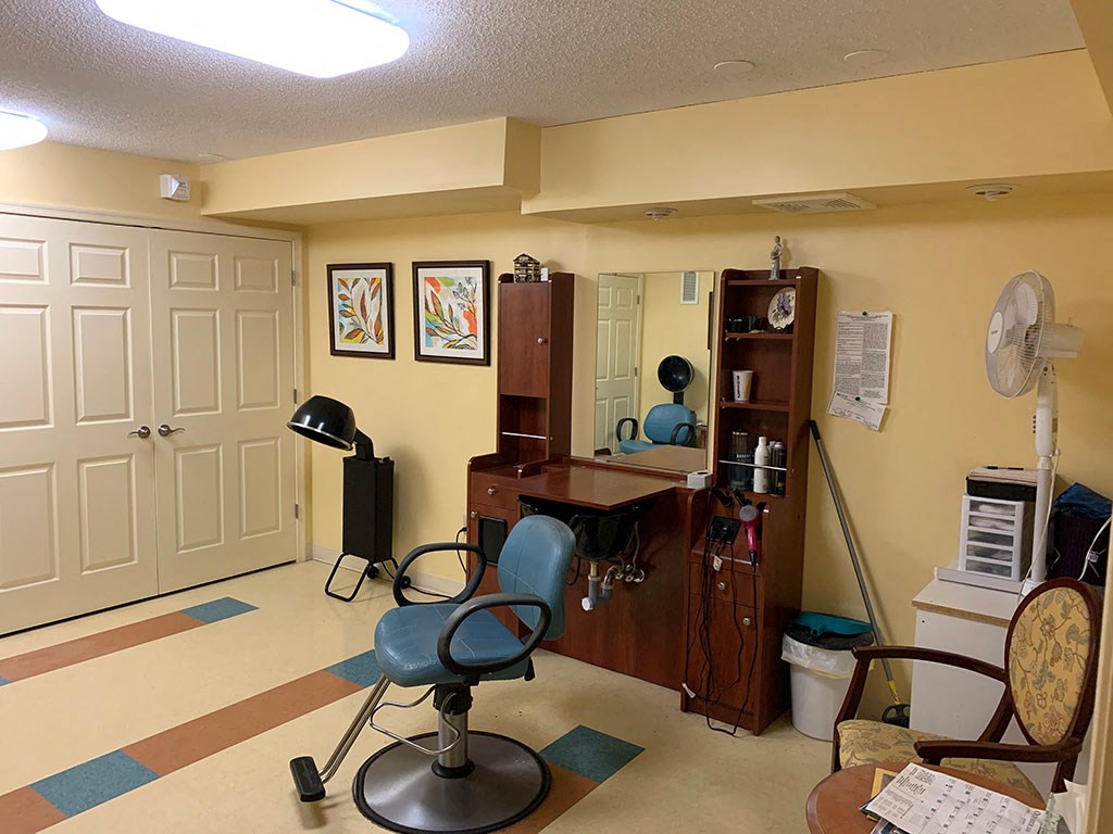 a living room with a desk and chairs and a fan