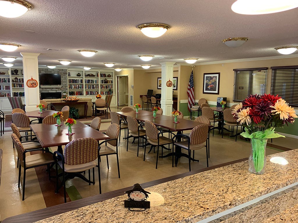 a dining room with tables and chairs and a counter with flowers
