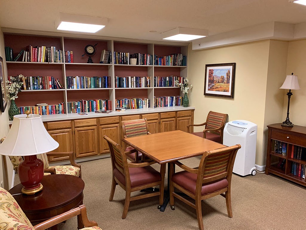 a library with a table and chairs and a book shelf