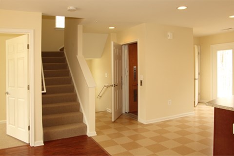A hallway with a staircase and a checkered floor.