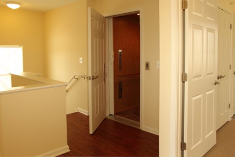 A hallway with a white door on the right and a brown door on the left.