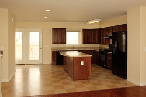 A kitchen with a black refrigerator and brown island.