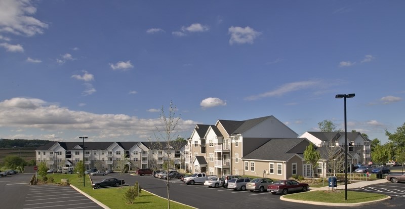 an architectural rendering of an apartment complex with cars parked in a parking lot