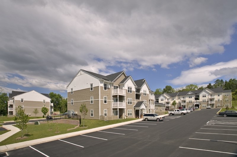 a street view of an apartment complex with cars parked in a parking lot