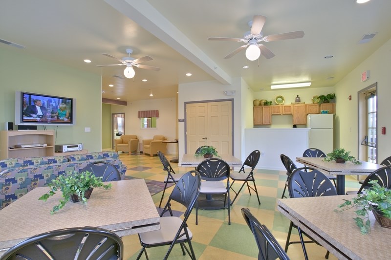 a dining room with tables and chairs and a living room with a television