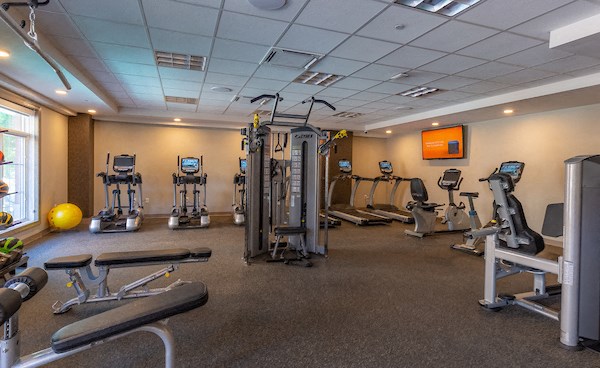 a gym with cardio equipment and weights on the floor