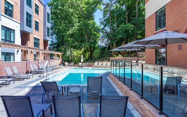 a swimming pool with chairs and umbrellas in front of a building