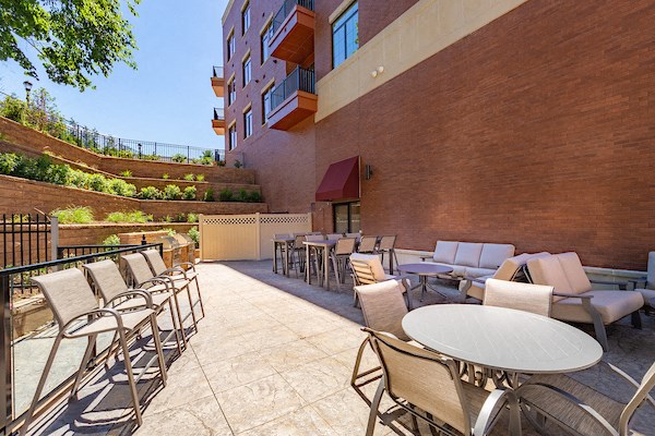 a patio with tables and chairs and a brick wall