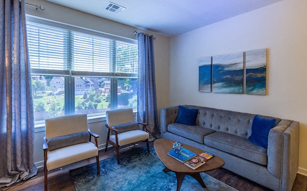 a living room with a couch and chairs and a large window