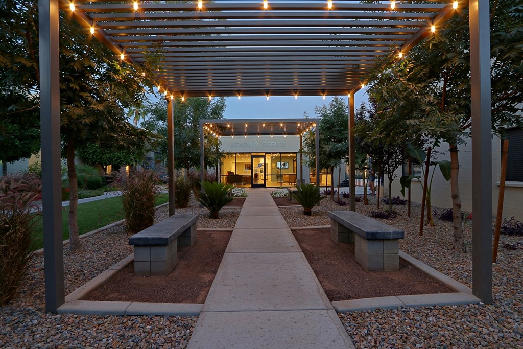 the courtyard is lit up at night with lights on the pergola