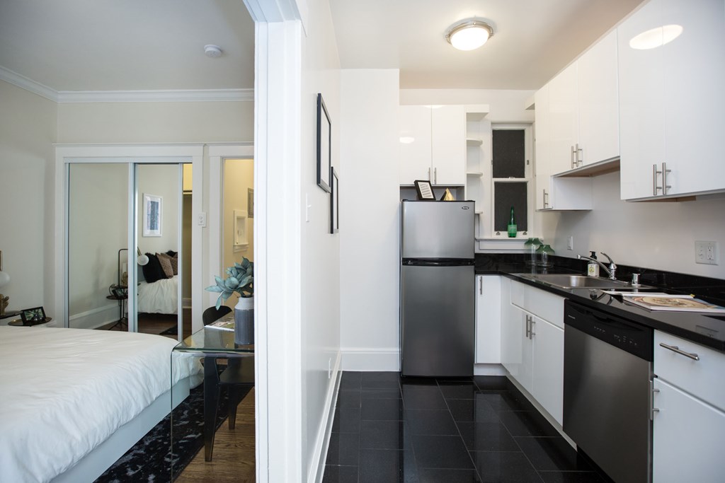 a bedroom and a kitchen with a sink and a refrigerator