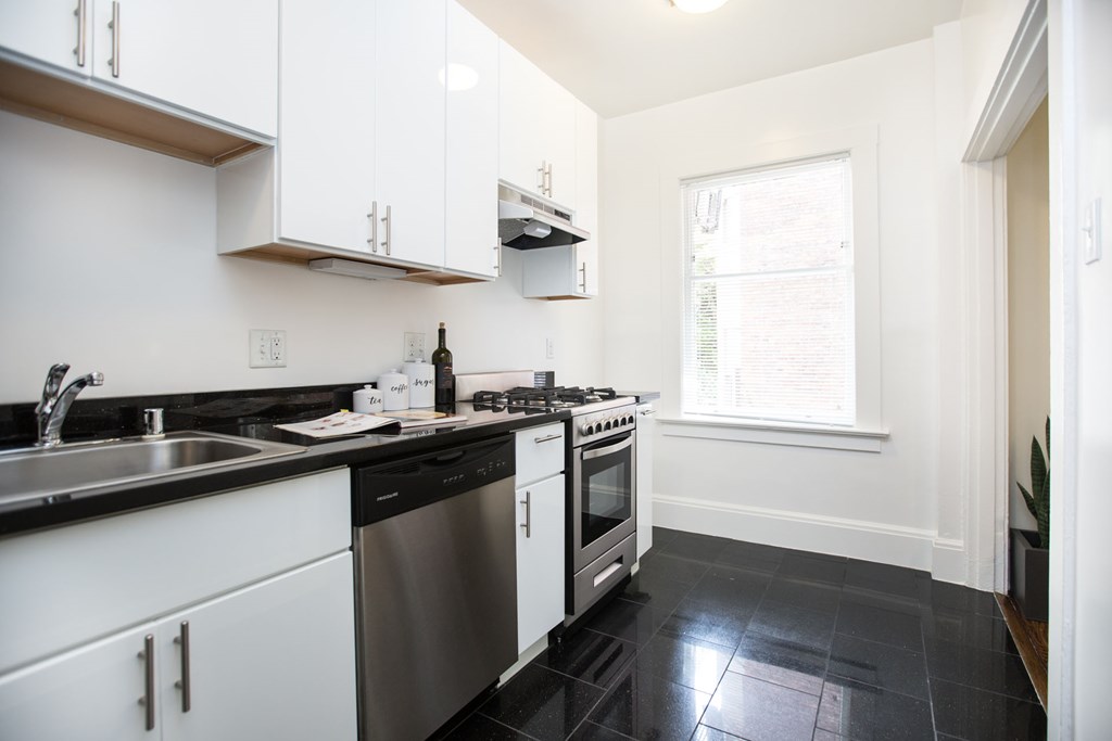a kitchen with white cabinets and stainless steel appliances and a window