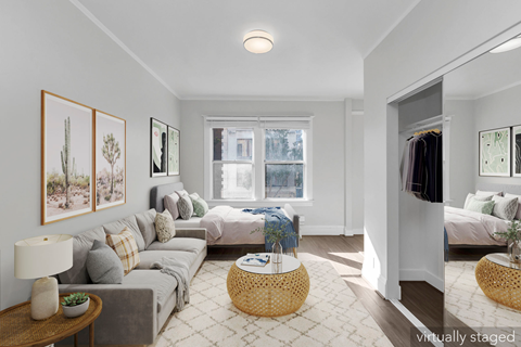 A living room with a grey couch, a wooden table, and a wicker ottoman.