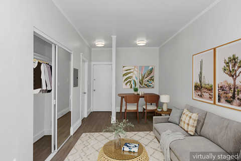 A living room with a grey couch, a coffee table, and a painting on the wall.