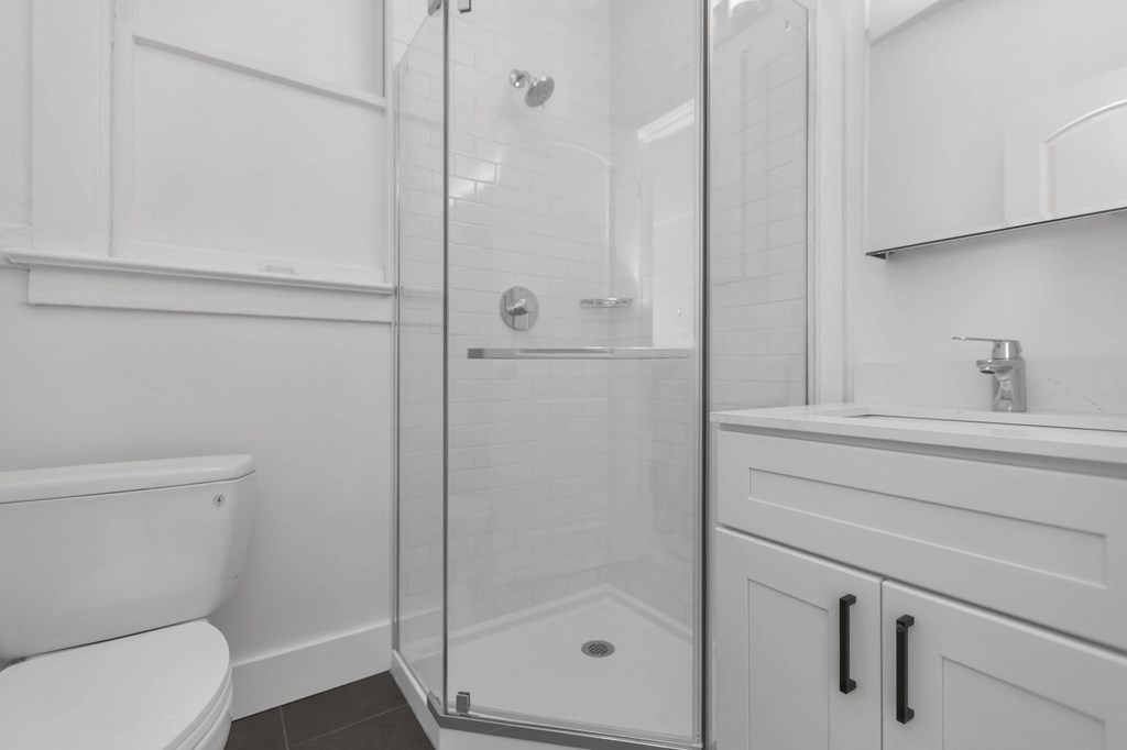 a white bathroom with a shower and a toilet