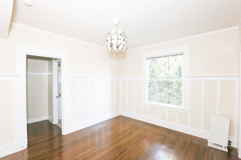 an empty room with white walls and a window and a chandelier