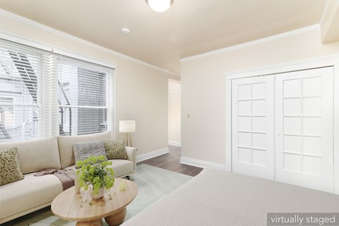 A living room with a couch, a table, and a window with blinds.