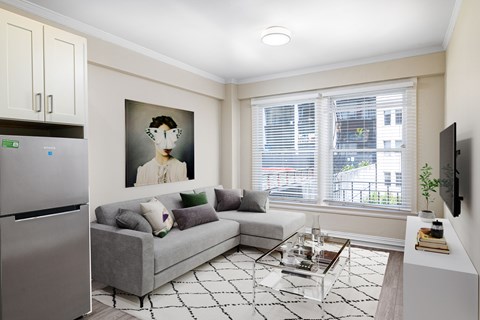 A modern living room with a grey couch and a painting on the wall.
