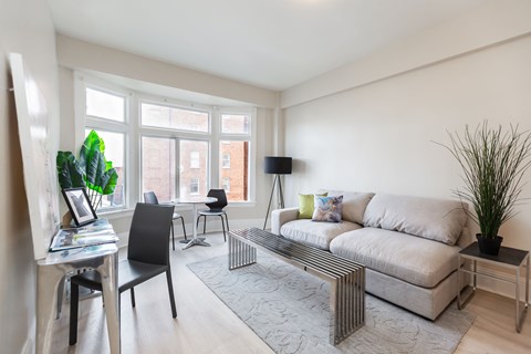 a living room with a couch and a desk and a large window