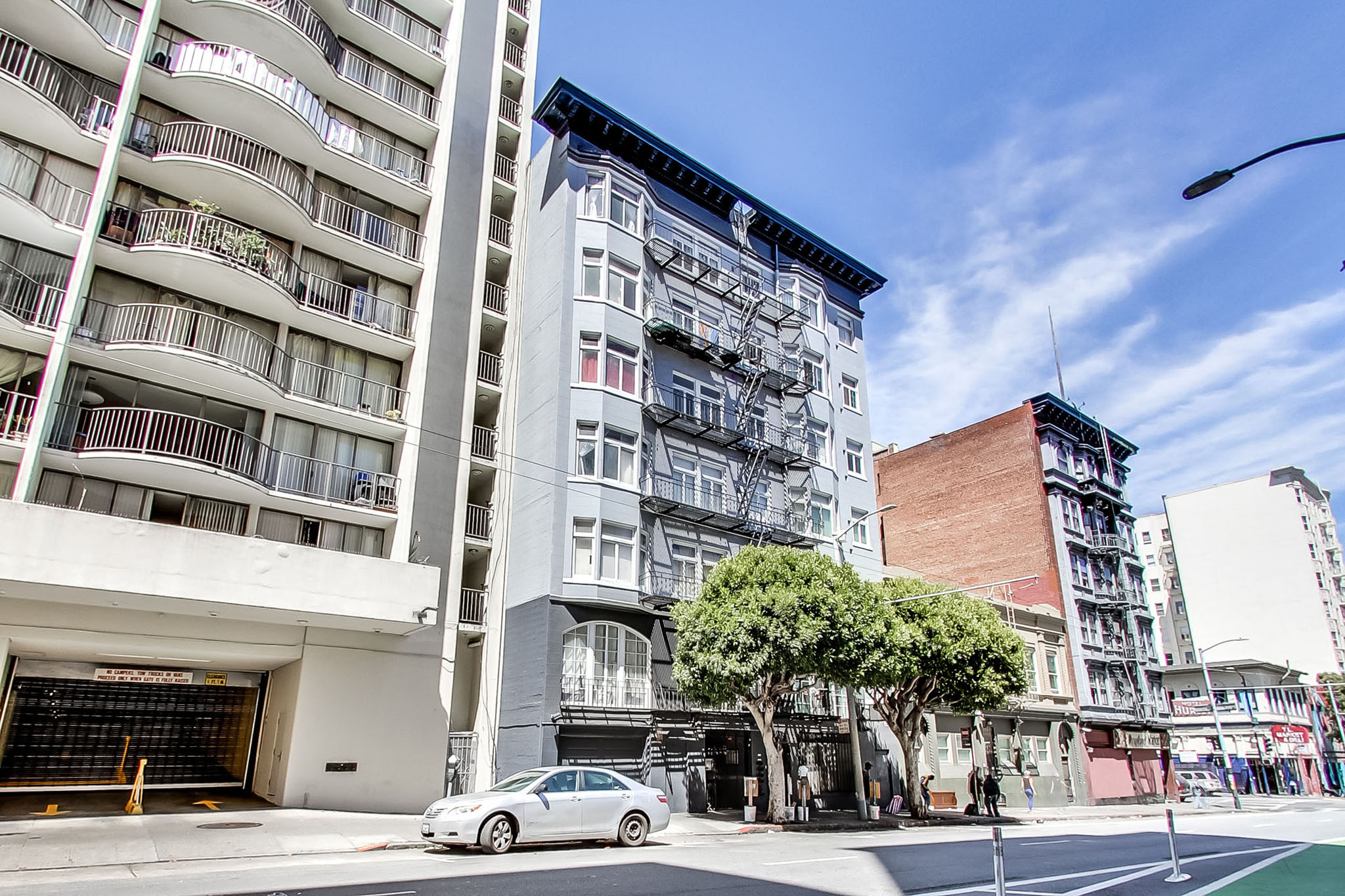 A white car is parked on the side of a street in front of a tall building.