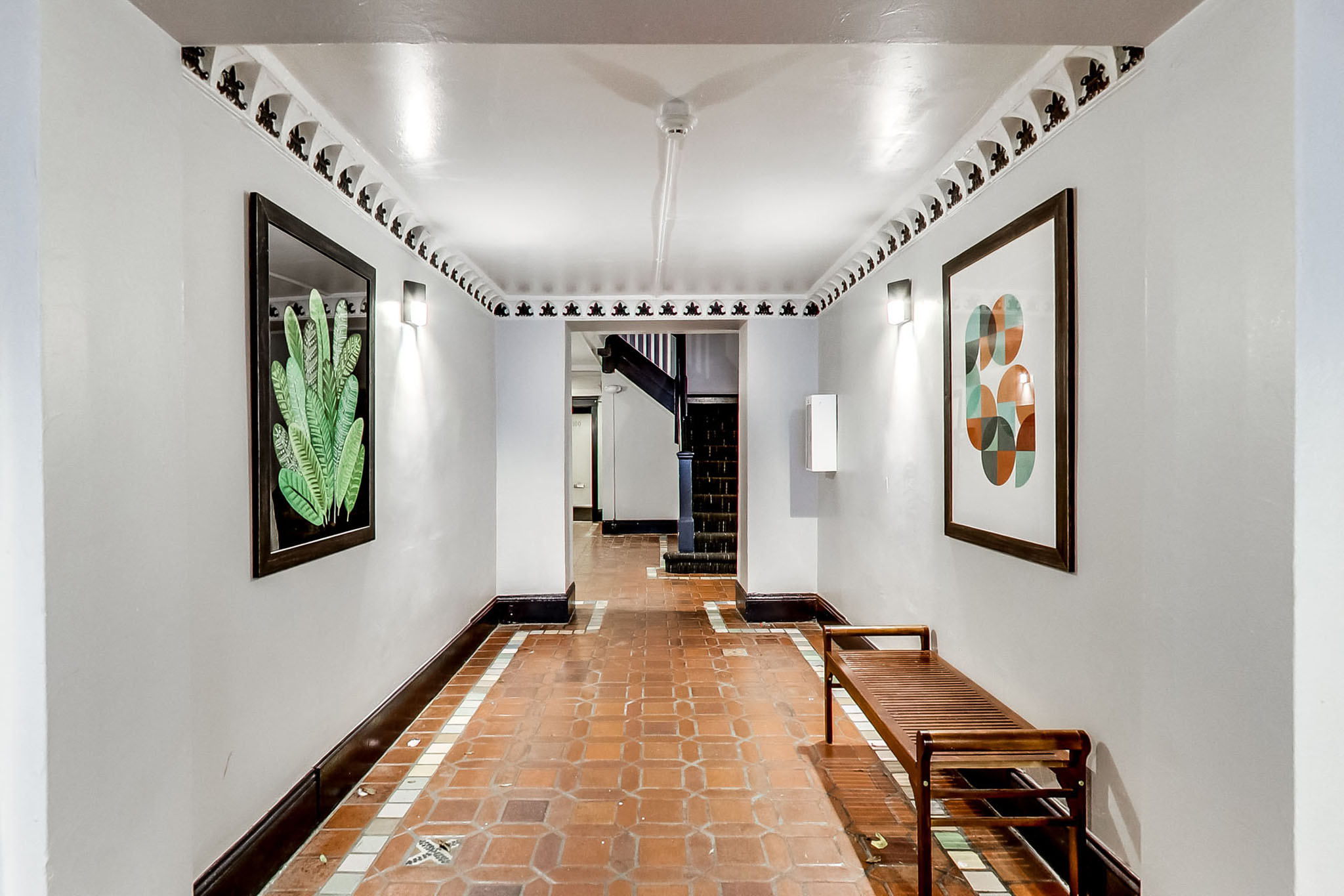A hallway with a bench and pictures on the wall.